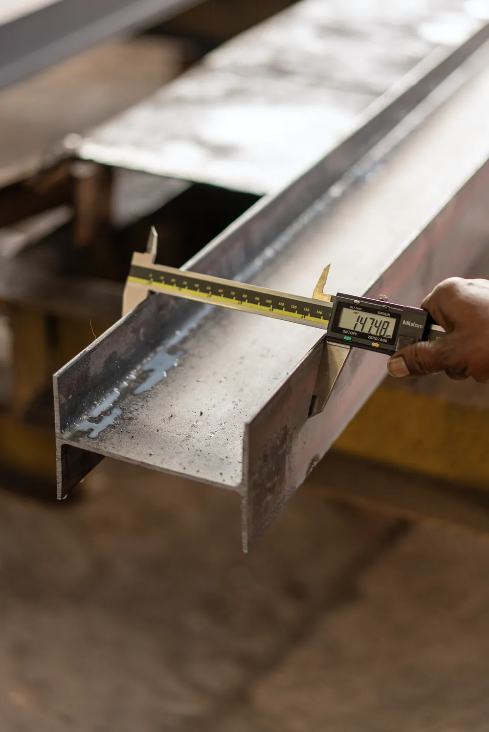 Digital caliper measuring the dimensions of a fabricated steel section.