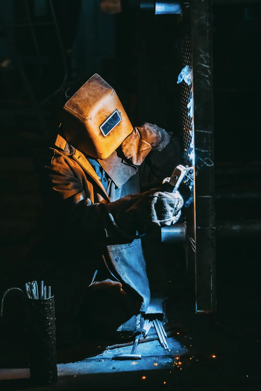 Welder using protective equipment during metal fabrication work.